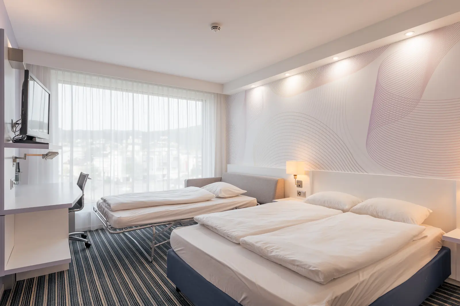 Hotelzimmer mit Doppelbett, Schreibtisch und grossem Fenster mit Blick über Affoltern am Albis
